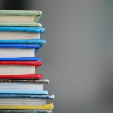 a stack of schoolbooks on a desk 